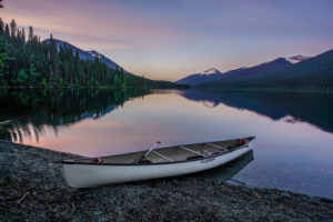 A white canoe lying at the lake, evening mood, with dreamlike mountain landscape A white canoe lying at the lake, evening mood, with dreamlike mountain landscape